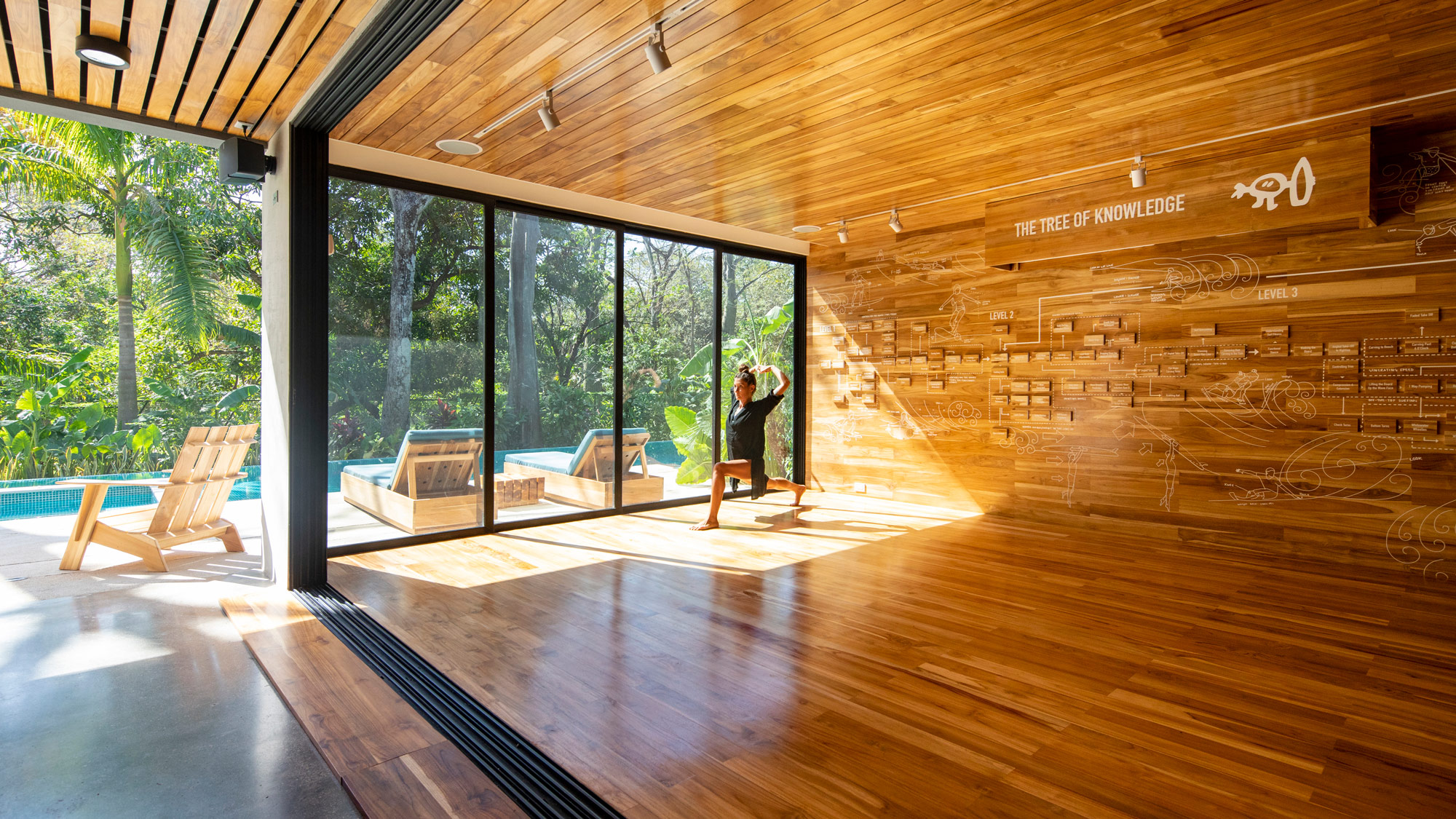 A person standing in a room with a wood floor and windows.