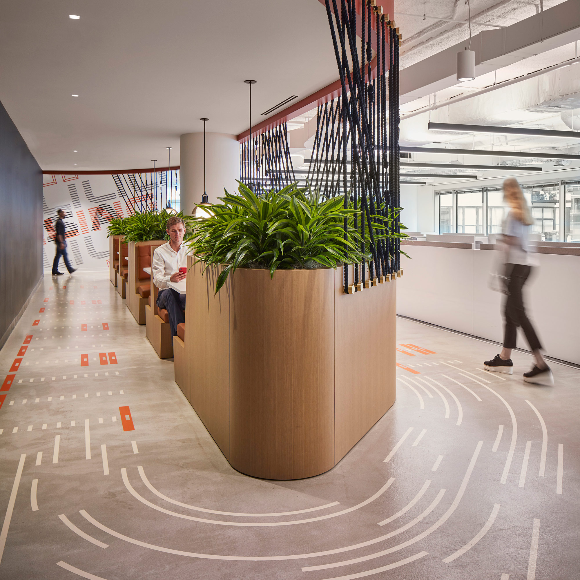A couple of people standing in a large building with a large potted plant.