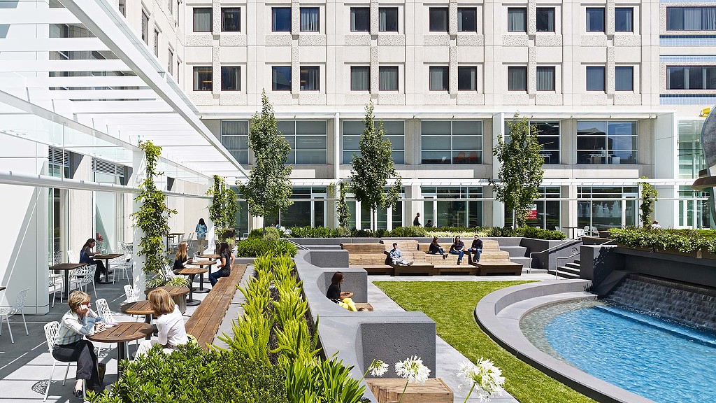 A building with a pool and people sitting at tables.