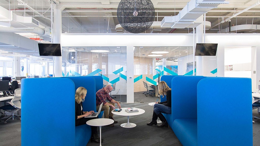 A group of people sitting in a room with blue chairs.