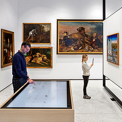 A man and a woman looking at art on the wall.
