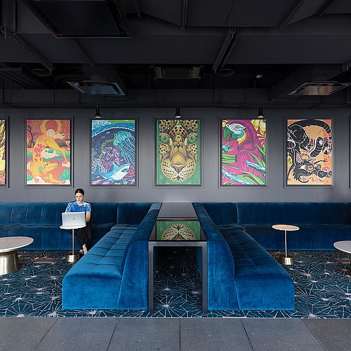 A person sitting on a bench in front of a wall of paintings.