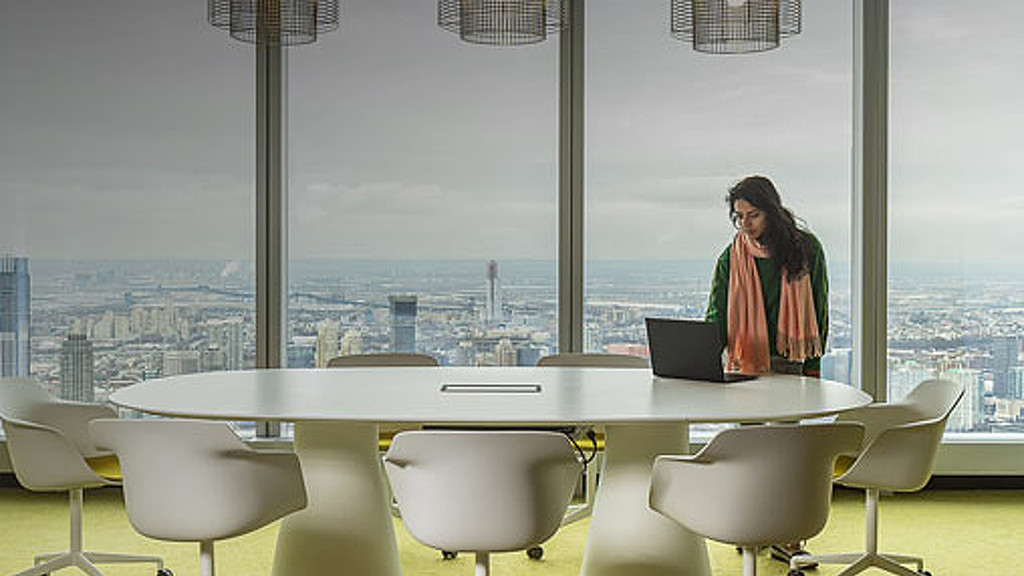A person standing next to a table with a laptop on it.