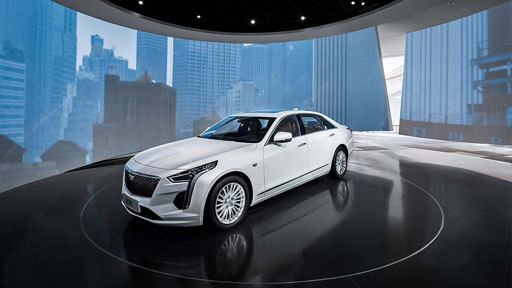 A white car parked in a large room with large windows.