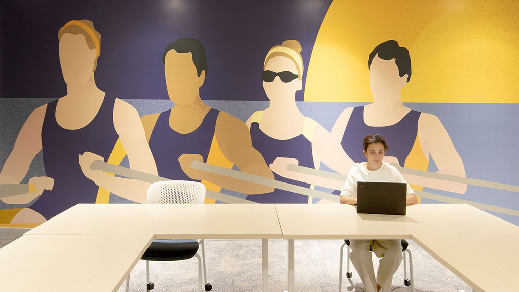 A person sitting at a table with a laptop in front of a group of people.